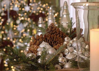 Three silver glass trees highlight a collection of natural evergreens, pinecones and glass ornaments on my buffet. A wooden bowl with ivory candles and green apples intertwined with silver beads rests on my coffee table.