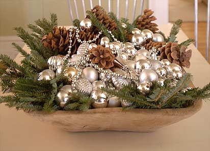 Brown pine cones, silver beads, and frosted ornaments in an antique dough trough add visual interest and carry the theme through to my dining table. It's a great conversation starter for my guests.